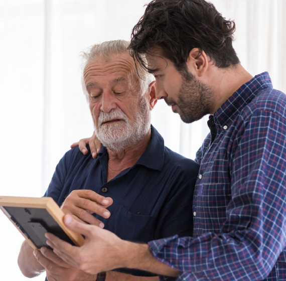 Senior man with son looking at a framed photo
