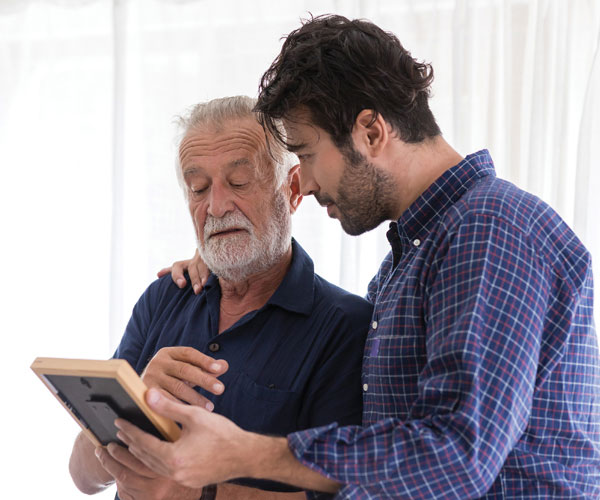 a elderly man and his adult son looking at a photo