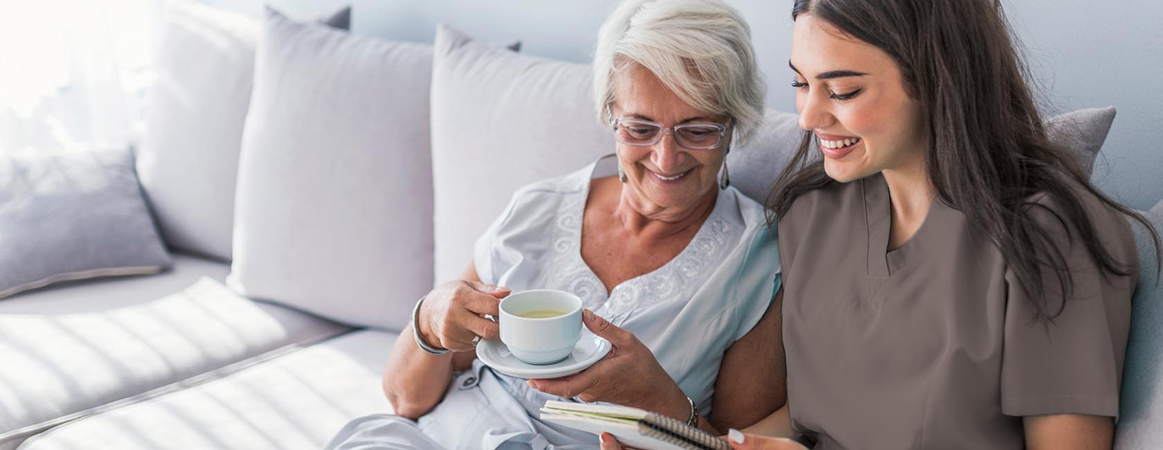 senior lady and healthcare worker looking at a small notebook together
