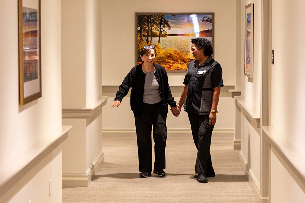 Senior woman walking in the hall with a nurse